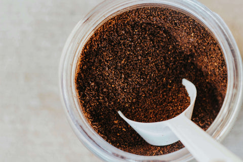 An image of a jar of coffee grounds with a coffee scoop.